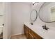 Well-lit bathroom featuring double sinks, oval mirrors, and modern fixtures at 28806 N 23Rd Ln, Phoenix, AZ 85085