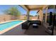 Relaxing covered outdoor patio with a gray sectional sofa, swimming pool and well-manicured lawn at 3063 N Heritage St, Buckeye, AZ 85396