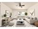 Bright living room featuring a ceiling fan, stylish decor, a light-colored sofa, and a large window at 3114 W Villa Maria Dr, Phoenix, AZ 85053