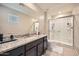 Well-lit bathroom boasts a walk-in shower with white tile, a large mirror, and granite countertops at 3916 S 79Th Ln, Phoenix, AZ 85043