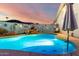 Backyard swimming pool featuring a rock waterfall and custom decorative wall art, set against a colorful twilight sky at 4013 E Delta Cir, Mesa, AZ 85206