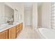 Bathroom featuring a soaking tub, glass block window, double sink vanity, and tile floors at 4701 W Fallen Leaf Ln, Glendale, AZ 85310