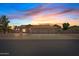 Inviting single-story home featuring a three-car garage and desert landscaping, bathed in the warm hues of a sunset sky at 4701 W Fallen Leaf Ln, Glendale, AZ 85310