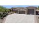 Wide driveway leading to a three-car garage with stone accents and desert landscaping at 6450 E Monterra Way, Scottsdale, AZ 85266