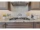 Close up of kitchen cooktop with stainless steel range hood and decorative backsplash tiles at 6450 E Monterra Way, Scottsdale, AZ 85266
