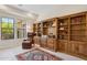 Office space features built-in wood bookcases, a comfortable reading chair, and bright natural light at 6450 E Monterra Way, Scottsdale, AZ 85266