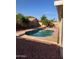 Backyard pool surrounded by stone and rocks, with mature trees and privacy fence at 8254 E Posada Ave, Mesa, AZ 85212