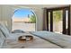 Close up of a comfortable main bedroom with an arched window offering scenic views at 8785 E Greenview Dr, Gold Canyon, AZ 85118