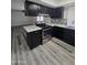 Modern kitchen with stainless steel appliances, marble countertops, black cabinets, and wood grain flooring at 8936 W Mackenzie Dr, Phoenix, AZ 85037