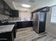 Modern kitchen featuring stainless steel appliances, marble countertops, black cabinets, and wood grain flooring at 8936 W Mackenzie Dr, Phoenix, AZ 85037
