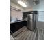 Modern kitchen featuring stainless steel refrigerator and sink, black cabinetry, and wood grain flooring at 8936 W Mackenzie Dr, Phoenix, AZ 85037