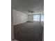Open concept living room with plush neutral carpet, white walls, a ceiling fan fixture, and natural light at 8936 W Mackenzie Dr, Phoenix, AZ 85037