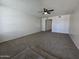 Spacious living room featuring plush neutral carpet, white walls, and contemporary ceiling fan fixture at 8936 W Mackenzie Dr, Phoenix, AZ 85037