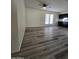 Bright living room with wood grain flooring, white walls, ceiling fan fixture, and a view to the kitchen at 8936 W Mackenzie Dr, Phoenix, AZ 85037