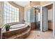 A soaking tub with glass block windows is featured in this luxurious primary bathroom at 9693 N 129Th Pl, Scottsdale, AZ 85259