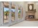 Bright living room features a fireplace and french doors that lead to an outdoor desert landscape at 9693 N 129Th Pl, Scottsdale, AZ 85259