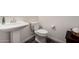 This bathroom features a pedestal sink and toilet against neutral walls and dark wood-look floors at 1217 E Monte Way, Phoenix, AZ 85042