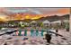 Backyard pool reflects a vibrant sunset and mountain views, surrounded by desert plants in decorative pots at 1217 E Monte Way, Phoenix, AZ 85042