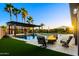 Backyard featuring a pool, fire pit, and covered pergola with seating surrounded by palm trees at 18371 W Roma Ave, Goodyear, AZ 85395