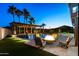 Beautiful backyard oasis featuring a pergola, pool, and fire pit surrounded by palm trees and seating at 18371 W Roma Ave, Goodyear, AZ 85395