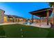 Expansive backyard with a pool, pergola, putting green, and lush landscaping, offering a resort-style experience at 18371 W Roma Ave, Goodyear, AZ 85395