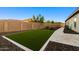 Backyard features an artificial turf lawn, mature trees, stone pavers, and lush landscaping at 18371 W Roma Ave, Goodyear, AZ 85395