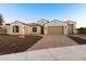 Charming single-story home with a three-car garage, desert landscaping, and a brick driveway at 18371 W Roma Ave, Goodyear, AZ 85395