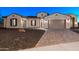 Home exterior showcasing a three-car garage, gravel landscaping, and a brick paver driveway at 18371 W Roma Ave, Goodyear, AZ 85395