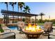 Inviting outdoor fire pit area with comfortable seating overlooking the pool and pergola at 18371 W Roma Ave, Goodyear, AZ 85395