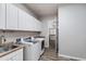 Well-lit laundry room featuring modern washer and dryer, ample storage, and a convenient sink at 18371 W Roma Ave, Goodyear, AZ 85395