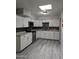 Modern kitchen boasts sleek white cabinets, stainless steel appliances, and eye catching black and white mosaic tile backsplash at 2019 E Southern Ave, Phoenix, AZ 85040