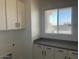 Practical laundry room with storage cabinets, granite countertops, and natural light from the window at 231Xx W Gloria Ln, Wittmann, AZ 85361