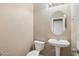 Cozy powder room with pedestal sink, toilet, oval mirror and neutral wall paint at 2947 N Evergreen St, Buckeye, AZ 85396