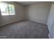 Empty bedroom with neutral carpet, large window, and a closet to maximize space at 3810 W Yucca St, Phoenix, AZ 85029