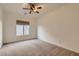 Carpeted bedroom featuring a ceiling fan, window with blinds, and light-colored walls at 42625 W Sandpiper Dr, Maricopa, AZ 85138