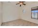 Bright bedroom features neutral carpet, window, ceiling fan, and fresh white paint at 42625 W Sandpiper Dr, Maricopa, AZ 85138