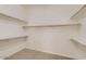 Walk-in closet featuring neutral carpeting and lots of shelving for storage and organization at 42625 W Sandpiper Dr, Maricopa, AZ 85138