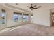 Bright main bedroom overlooking a serene lake view, featuring multiple windows and a ceiling fan at 42625 W Sandpiper Dr, Maricopa, AZ 85138