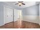 Bedroom includes hardwood flooring, a ceiling fan, base trim and an entry door with a view to the adjacent stairwell at 7108 W Morrow Dr, Glendale, AZ 85308