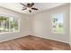 Bedroom with hardwood floors, a ceiling fan, and two windows with views to exterior greenery and mature trees at 7108 W Morrow Dr, Glendale, AZ 85308