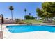 Sparkling blue pool surrounded by lush landscaping and a wrought iron fence at 7108 W Morrow Dr, Glendale, AZ 85308