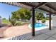 Covered patio overlooks pool surrounded by desert landscaping and a white fence, shaded by a wooden pergola at 7108 W Morrow Dr, Glendale, AZ 85308