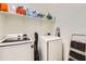 Practical laundry room with front-load washer and dryer, shelves, and an ironing board at 7665 W Fetlock Trl, Peoria, AZ 85383