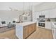 Open kitchen with white cabinets, stainless appliances, an island with waterfall edge, and open access to the living room at 7685 W San Miguel Ave, Glendale, AZ 85303