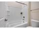 A clean and modern white bathtub with shower combo features built in shelving and neutral wall tile at 8027 W Northview Ave, Glendale, AZ 85303