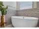 A luxurious soaking tub is enhanced by decorative gray tile and natural light from a window with blinds at 8027 W Northview Ave, Glendale, AZ 85303