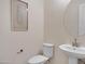 This stylish half-bathroom offers a pedestal sink, toilet, and attractive wall art with a round mirror at 8027 W Northview Ave, Glendale, AZ 85303