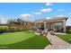 Beautiful backyard with a putting green, fire pit, and an outdoor kitchen area, ideal for relaxation and gatherings at 8820 E Ivy Cir, Mesa, AZ 85207