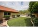 Spacious backyard with lush artificial turf, patio, a white fence, and mature landscaping provides a private oasis at 9085 E Windrose Dr, Scottsdale, AZ 85260