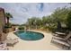 Backyard view featuring a sparkling pool, a lounge area with sunbeds and mature landscaping creates a relaxing environment at 9085 E Windrose Dr, Scottsdale, AZ 85260